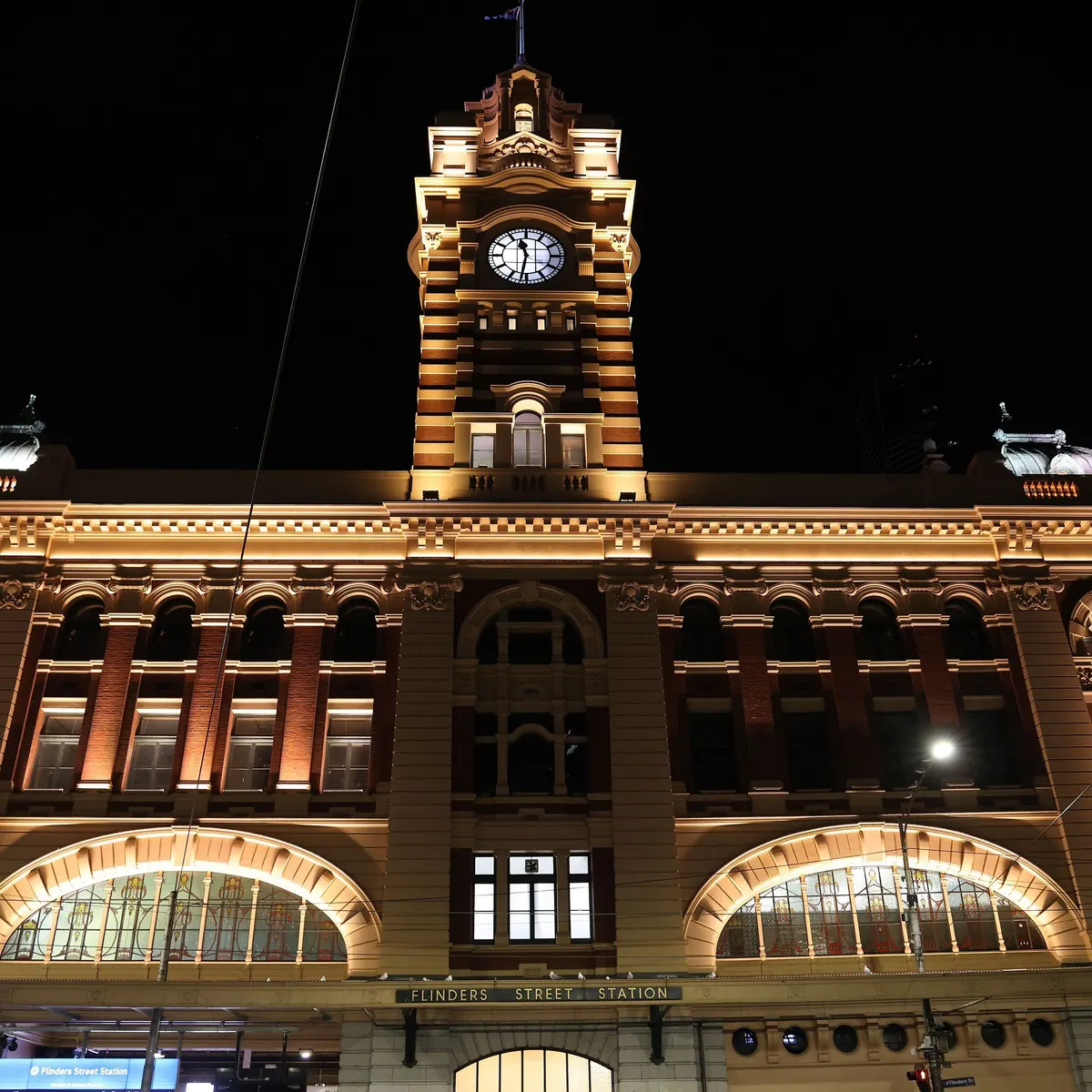 Clock tower and entrance of Flinders Street Station lit at night in Melbourne